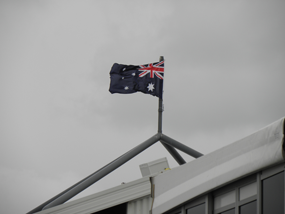鉛色の空にオーストラリアの旗がへんぽんとはためく。つまりそれだけ天気が悪くて風が強い、ということですよ。