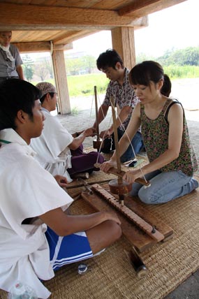 これが弥生時代に使われていたという火おこしの道具。「舞切り式」と言われる方法だ。二人とも必死だ。ガイドのオジサンに見守られているからね。熱くなって暑くなった。